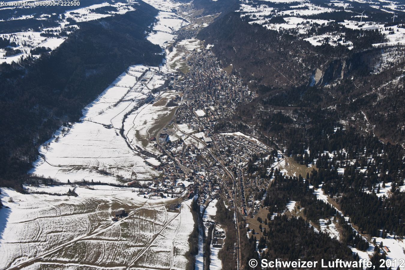 St. Imier im 'Vallon de Saint - Imier' (Position: 2'566'470.34, 1'222'756.89), Blick Rchtg SW. Stadtteil vorne im Bild: Villeret. Bildmitte: St-Imier Centre. Im hintern Bildteil: 'Les Fontenayes'. Hügelzug rechts: 'Montagne du droit'. Flusslauf links im Bild: 'La Suze'. Hügelzug links: zum Chasseral. - St. Imier wird im Umland deutsch
